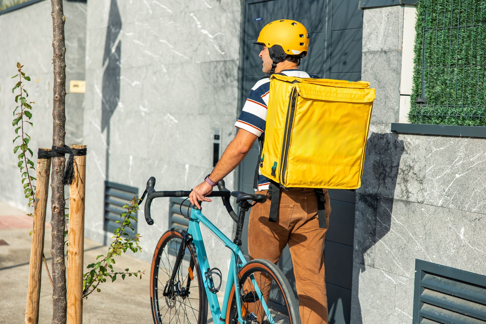 Entregador com mochila térmica andando de bicicleta na rua